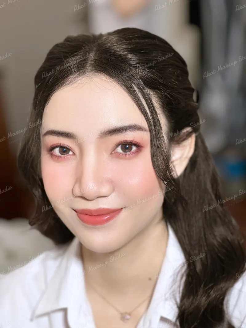 ใบหน้าสว่างใสแต่งตาโทนชมพูแดง ปัดแก้มชมพูอ่อน ลิปสีโอลด์โรส ผมดำยาวม้าปัดข้างเปิดหน้า เสื้อนักศึกษาสีขาว